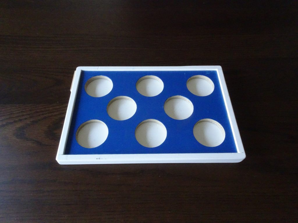 平面上に8つの丸い穴がある台と、8つの円盤の教具のイメージ