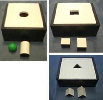 ３つの教具の写真。ひとつめは円の穴に、球体や円柱を通す教具。ふたつめは、四角の穴に立方体や直方体を通す教具。みっつめは、三角の穴が開いた台に三角柱を通す教具